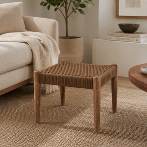 Woven wooden stool in a living room setting with a beige sofa and decorative items.