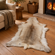Light Brown Reindeer Hide on wooden floorboards in front of a log burner, beside a cream sofa and a log basket