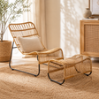 Murano rattan chair and footstool set in a room with plants and wooden furniture.