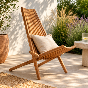 Murano wooden lounge chair with a pillow on a patio with plants and a table in the background