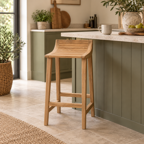 A light natural wood bar stool with a slatted seat and backrest, positioned in a modern kitchen next to a sage green island with a stone countertop.