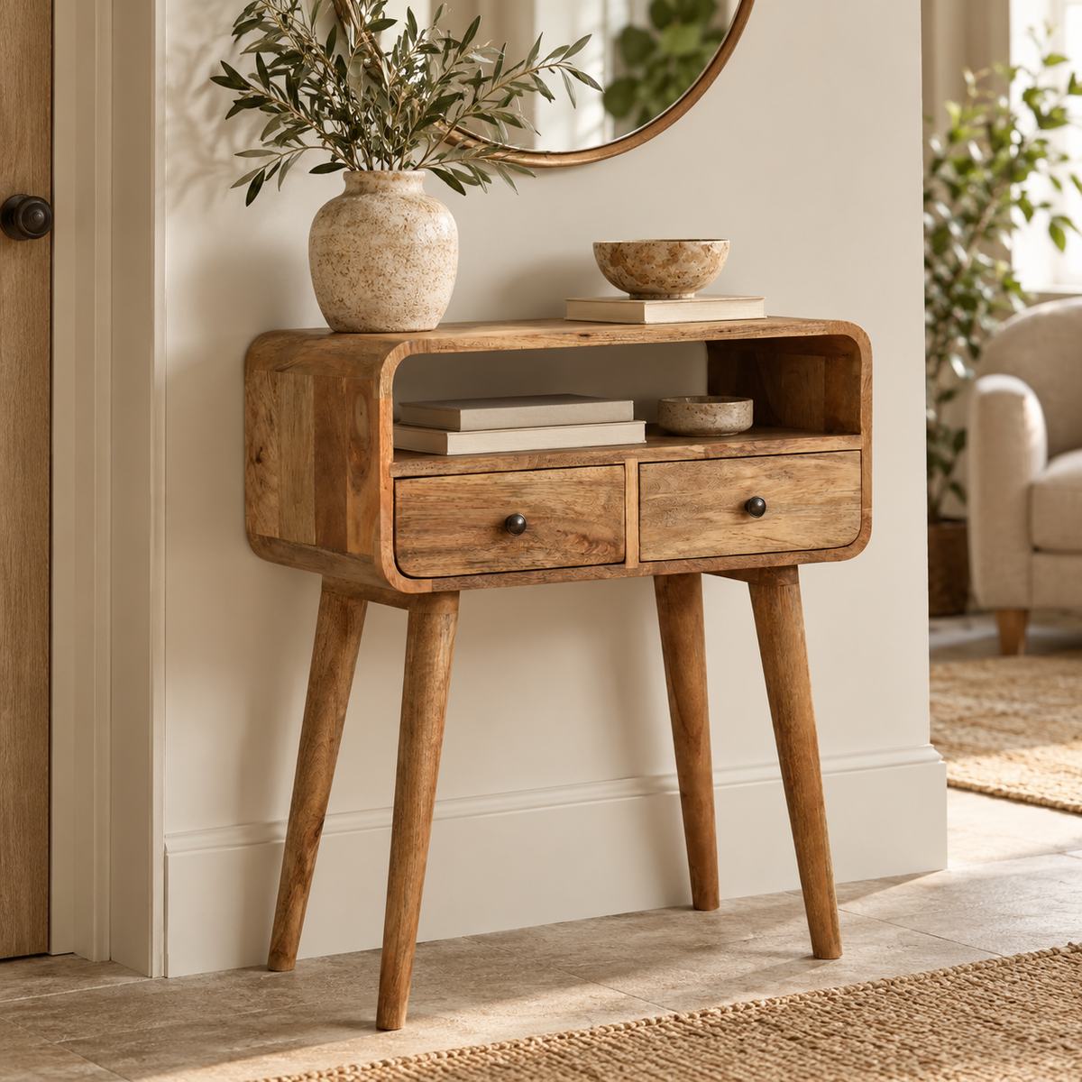 A mid-century modern wooden console table with two drawers and tapered legs, styled in a warm, neutral-toned living room setting.