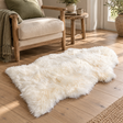 Natural Sheepskin XXL Rug on a wooden floor beside a wooden armchair and a small wooden side table