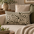 Elora Natural And Green Rectangular Cushion with cream arches on olive green, on a linen sofa with a knitted throw and olive branches