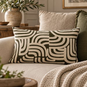 Elora Natural And Green Rectangular Cushion with cream arches on olive green, on a linen sofa with a knitted throw and olive branches