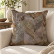 Tierra Grey Chevron Hair on Leather Patchwork Cushion on a cream sofa, beside a stone vase of olive branches