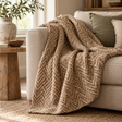 Zigra Beige Woven Throw with a brown chevron weave draped over a cream linen sofa, beside a rustic wooden side table and a jute rug