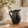 Olive Olpe Vase on a wooden table beside a stack of books, a rustic stone vase of olive branches and a wooden bowl