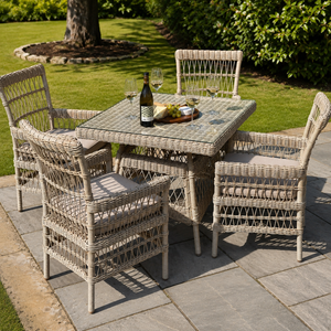 Outdoor patio set with wicker table and chairs on a stone patio.