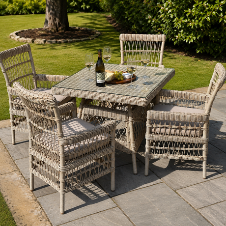 Outdoor patio set with wicker table and chairs on a stone patio.