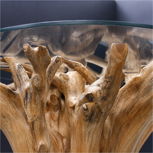 Close up of a round table made from the root of a teak tree with a glass top