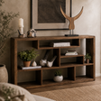A rustic dark brown wooden cubby shelf styled in a cozy living room setting, holding books, small potted plants, ceramic bird figurines, and decorative objects.