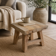 Wooden side table with a cup and book in a cozy living room setting.
