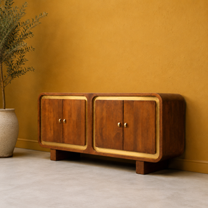 Wooden cabinet against a mustard yellow wall with a plant on the left.