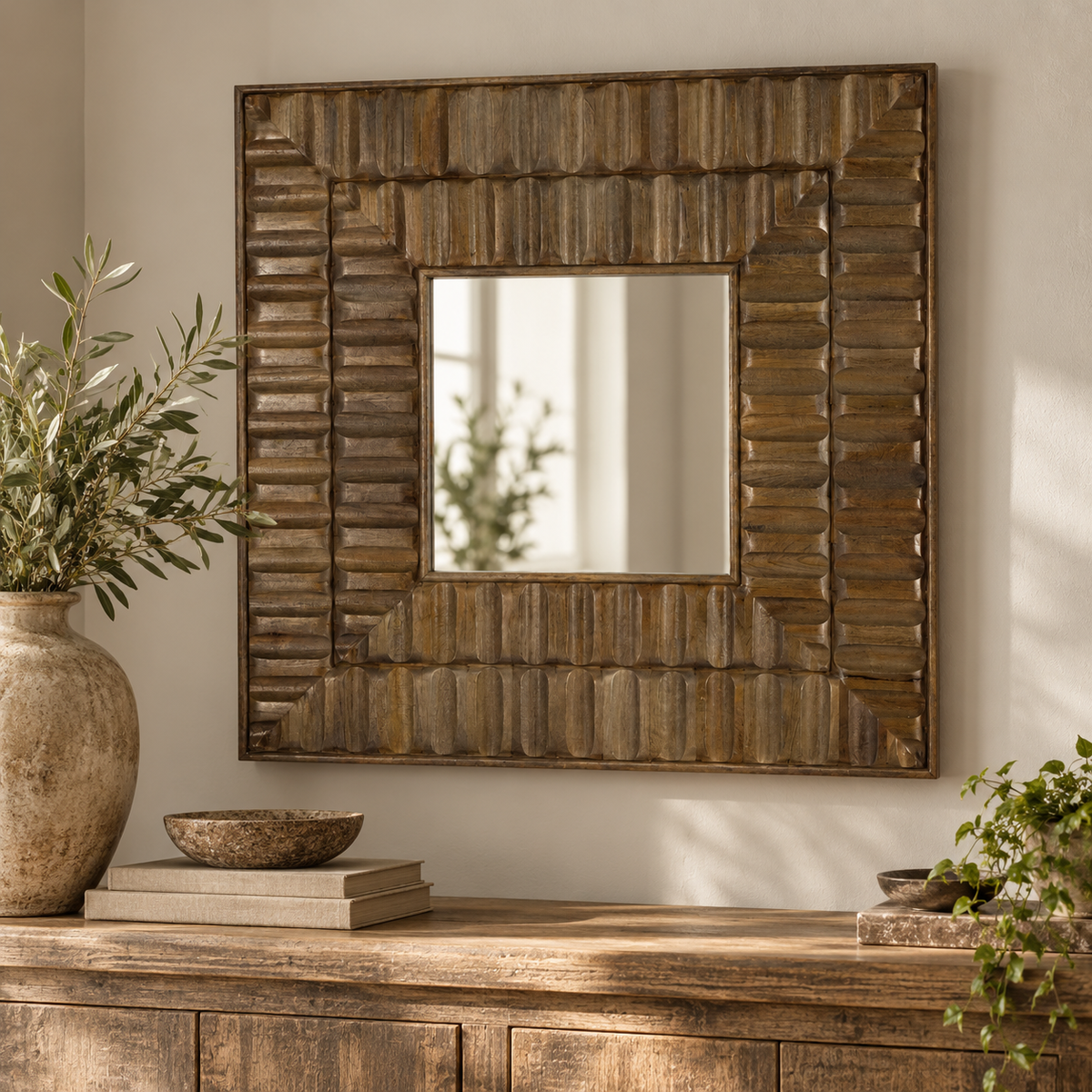 Sarana Tile Wooden Square Wall Mirror hung above a rustic wooden sideboard with a stone vase of olive branches, a wooden bowl and books