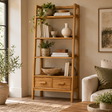 Wooden Ladder Bookshelf with Drawers, a sungkai wood bookcase styled with books, vases and plants in a cosy living room.