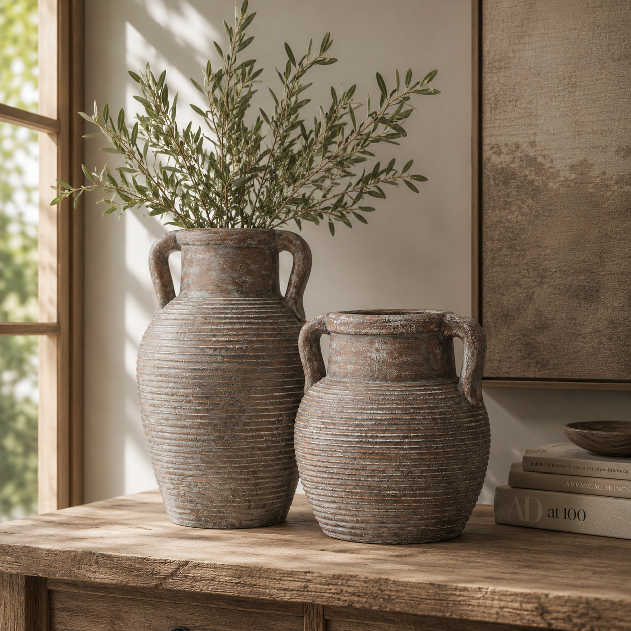 Two rustic ceramic vases with handles on a wooden surface, one containing greenery.