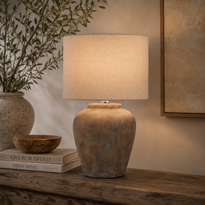 Decorative lamp on a wooden surface with books and a plant in the background