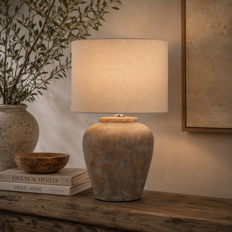 Decorative lamp on a wooden surface with books and a plant in the background
