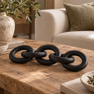Silva Black Wood 5 Link Chain Decor laid across a rustic wooden coffee table in front of a cream sofa, beside a stoneware vase of olive branches
