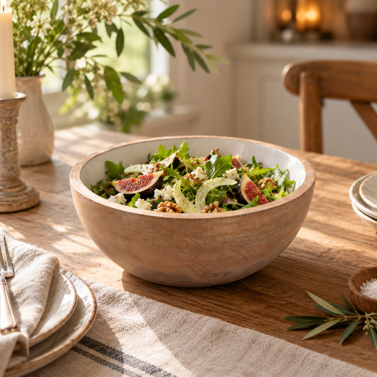 The Solace Mango Wood Round Serving Bowl filled with a fig and walnut salad on a rustic wooden dining table with linen napkins.