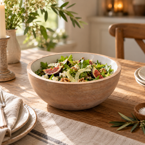 The Solace Mango Wood Round Serving Bowl filled with a fig and walnut salad on a rustic wooden dining table with linen napkins.