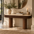 Solmere curved console table with travertine top and mango wood pillar legs, styled in a hallway beneath a round mirror