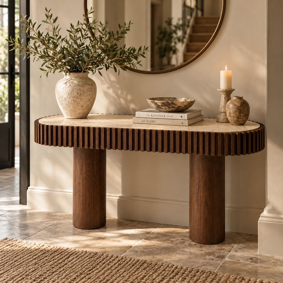 Solmere curved console table with travertine top and mango wood pillar legs, styled in a hallway beneath a round mirror