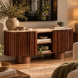Solmere curved media unit with travertine top and ribbed mango wood, styled with a stoneware vase, books and olive branches