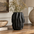 Soren Black Textured Bud Vase styled with dried stems on a rustic wooden table in a warm, neutral interior.