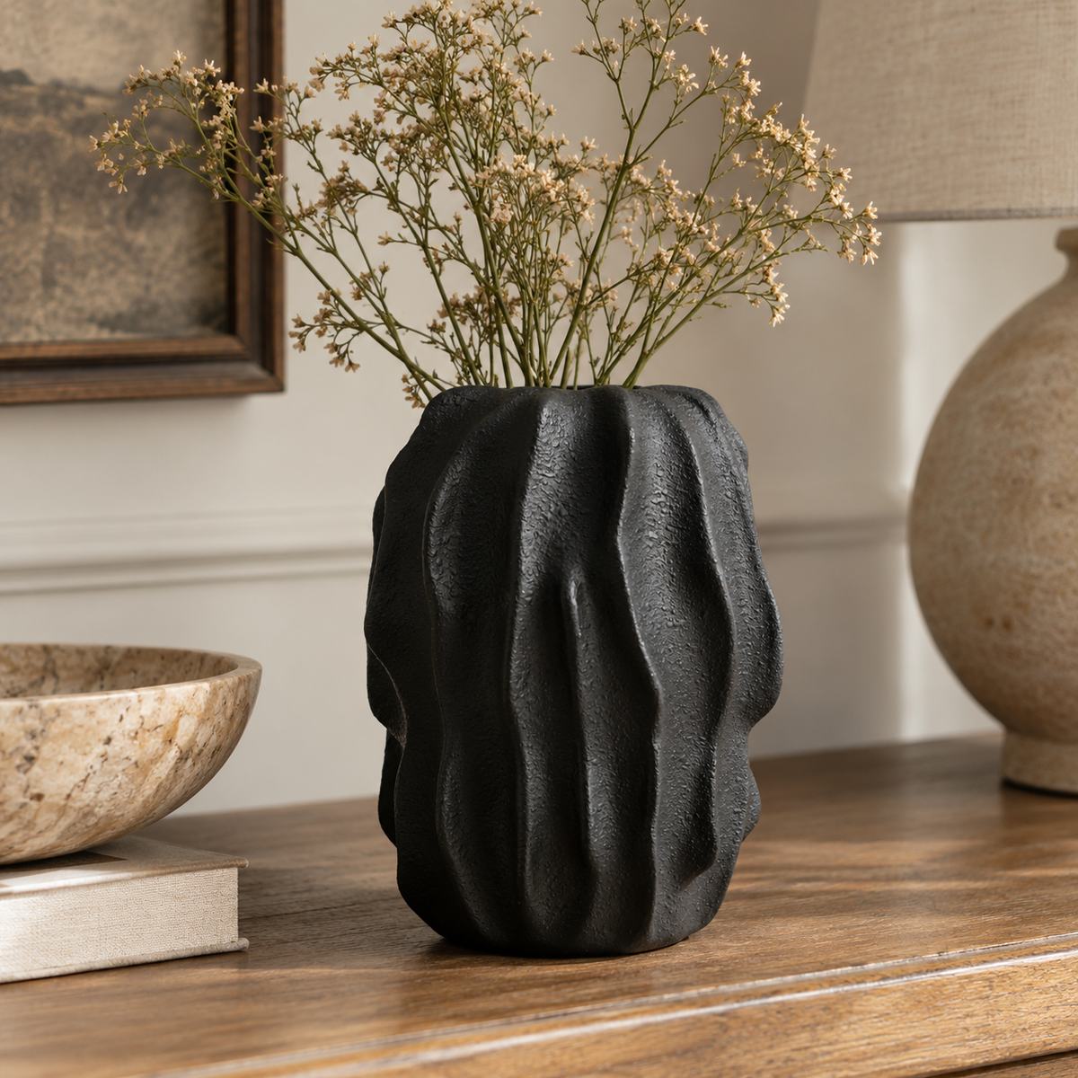 Soren Black Textured Bud Vase styled with dried stems on a rustic wooden table in a warm, neutral interior.