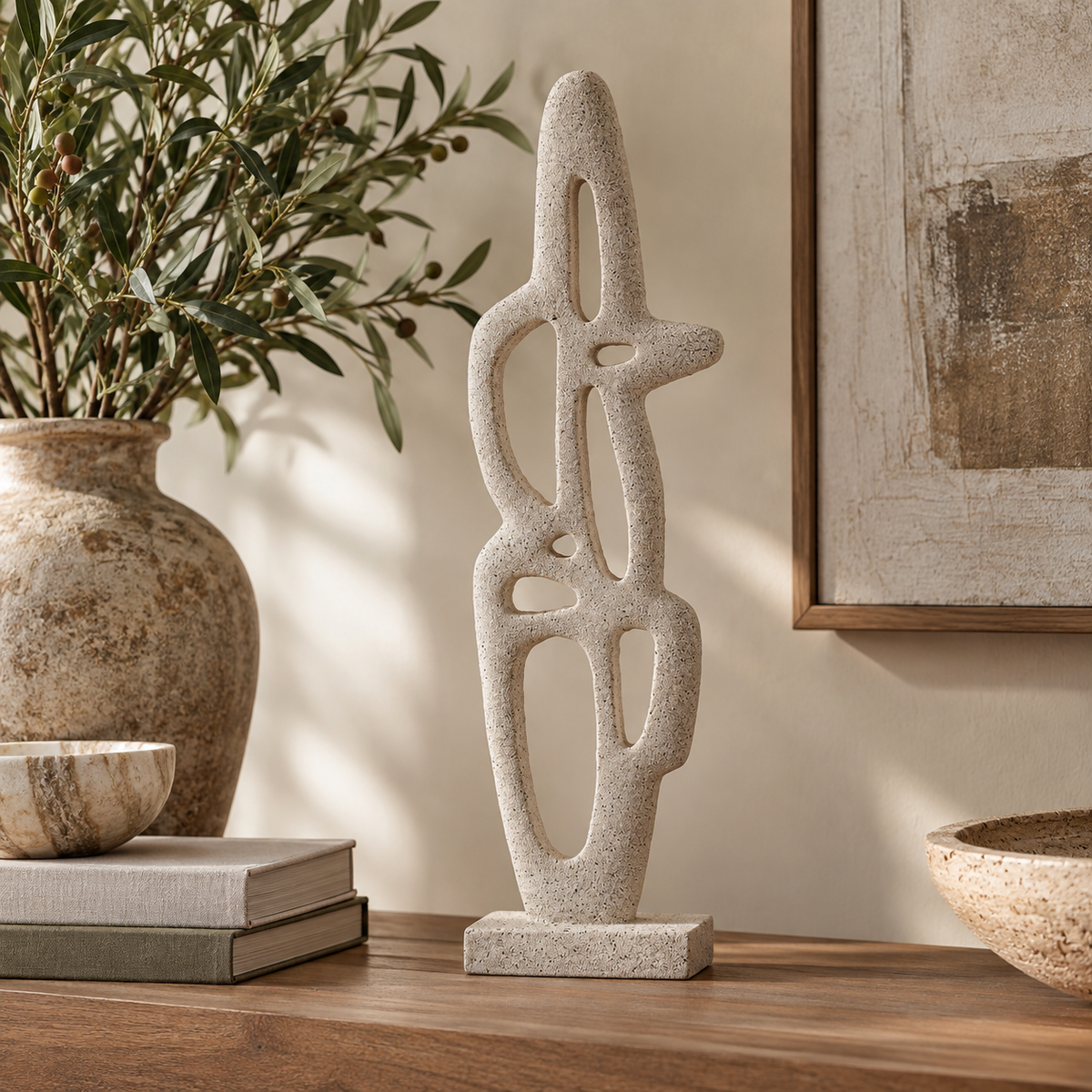 Soren Cream Textured Abstract Interlocking Sculpture displayed on a wooden console table in a warm, neutral interior, styled with an olive branch vase, books and natural decorative accents.