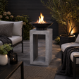 Outdoor patio setting with a fire pit on a concrete stand, surrounded by seating and plants.
