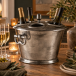 Sterling antique silver four bottle wine cooler holding wine bottles on a candlelit dining table
