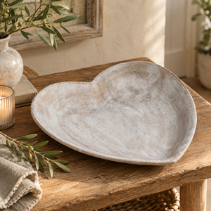 Stone Heart Dish on a wooden table beside olive branches, a lit candle and a linen napkin