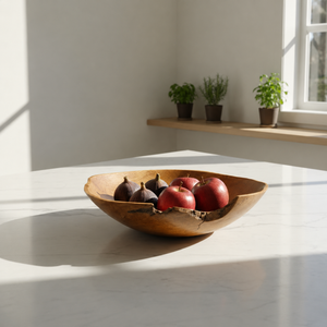Wooden bowl with fruits on a light surface with plants in the background