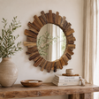 Round teak wooden mirror on a beige wall above a wooden console with a vase, books and a wooden bowl