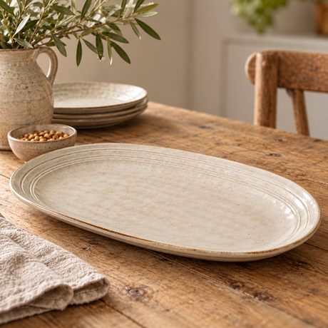 The Gable Collection Stoneware Large Oval Platter, an empty soft beige oval platter with ridged rings, on a rustic wooden table.