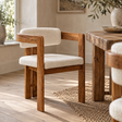 The Hawthorn Dining Chair in solid mango wood with a cream bouclé seat and curved back, beside a rustic wooden dining table on a jute rug in a sunlit room.