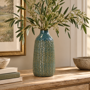 Teal ceramic vase with an intricate raised textured pattern, styled with olive branches on a rustic wooden table.