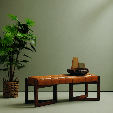 Tierra leather bench with wooden base against a pale green background with a tall plant