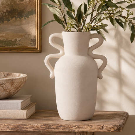 Tova White Tall Vase with Abstract Handles styled on a rustic wooden console with leafy branches.