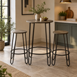 A three-piece bar stool set in a bright kitchen setting, featuring a central round high-top table and two matching bar stools with rustic wood-look seats and black metal hairpin legs.