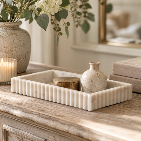 Vela White Marble Fluted Rectangular Tray on a weathered wooden dresser, holding a brass trinket box and a small stoneware bottle beside a candle.