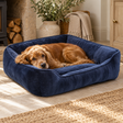 Cocker spaniel asleep in the Velvet Navy Dog Bed on a sunny stone floor by a log store