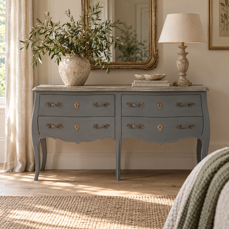 Vienne 4 Drawer Double Chest of Drawers in a bedroom beneath a gilt mirror, styled with a vase of olive branches and a table lamp