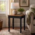 Living room with a wood and black side table, lamp, and books near a sofa.