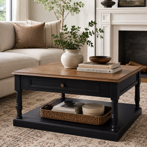 Black painted coffee table with natural oak top in a living room with books, a vase, and a plant on top