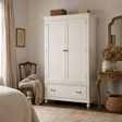 White wardrobe in a bedroom with wooden chair and table.