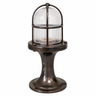 An industrial nautical-style table lamp with a ribbed clear glass dome under a dark bronze metal cage, mounted on a matching dark bronze flanged base.